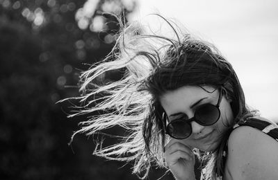 Close-up of young woman wearing sunglasses in the wind