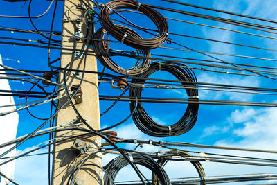 Low angle view of electricity pylon against blue sky