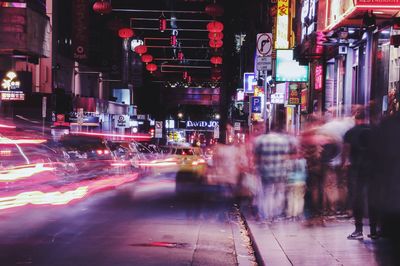 Blurred motion of people on sidewalk at night