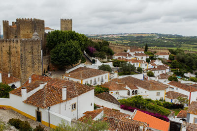 High angle view of houses in medieval town of obidos with castle against sky