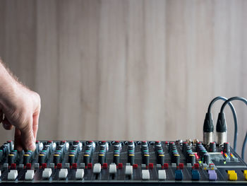 Cropped hand of male dj playing music on sound mixer against wall