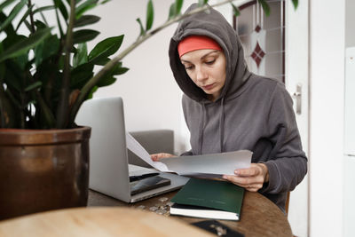 Young woman using laptop while sitting on table