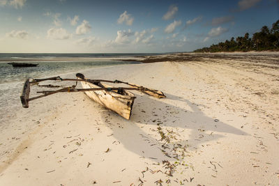 Boat on sand at beach against sky