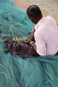 High angle view of man repairing fishing net