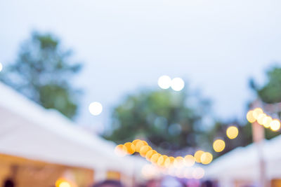 Defocused image of illuminated lights against sky