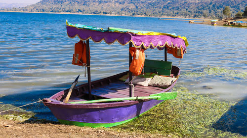 Boat moored on shore by lake