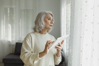 Senior woman holding digital tablet at home