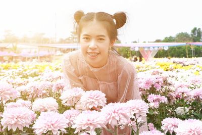 Portrait of smiling young woman against blue flowering plants