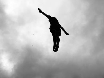 Low angle view of silhouette person jumping against sky