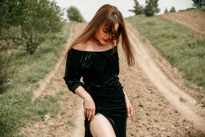 Beautiful young woman standing on dirt road