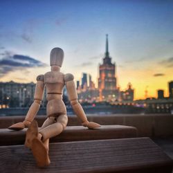 Close-up of wooden figurine on railing in city against sky