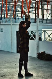 Side view of woman with arms raised touching paper streamers on ceiling