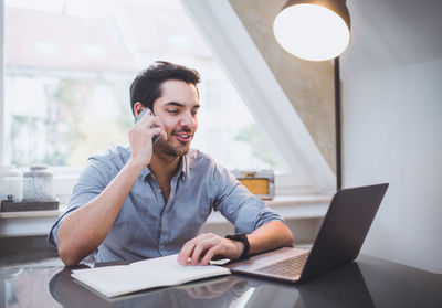 Young man using mobile phone while sitting on table