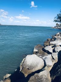 Rocks by sea against blue sky