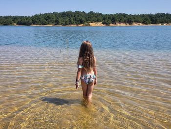 Rear view of girl wearing bikini standing in sea