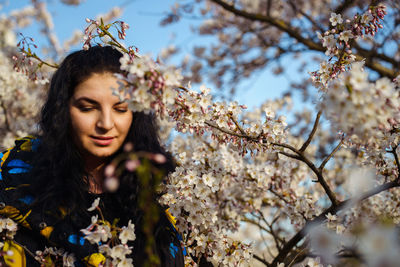 Attractive young woman enjoying spring among flowering trees in cherry orchard