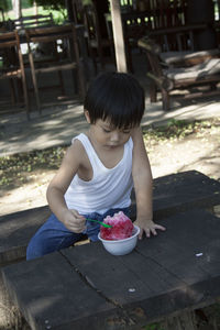 Boy eating flavored ice while sitting on table