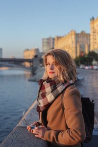 Portrait of woman against river in city