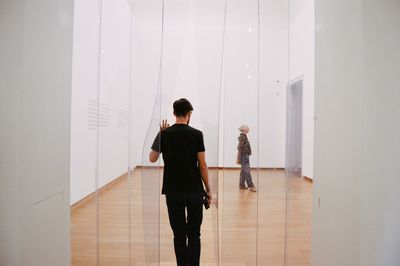 Rear view of two women walking in corridor