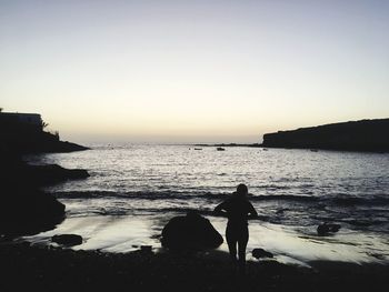 Rear view of women on beach against clear sky