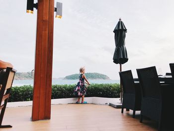 Girl standing at restaurant against sky