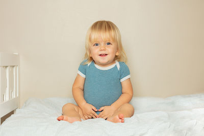 Portrait of cute girl sitting on bed at home