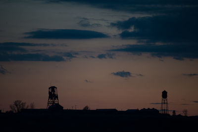 Silhouette tower on land against sky at sunset