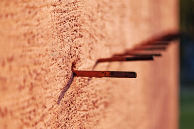 A row of metal sticks protruding from the orange concrete wall may be for defense or assembly