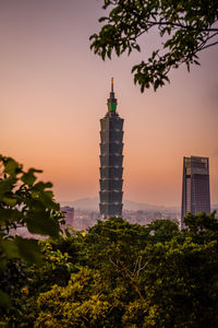 Trees and building against sky during sunset