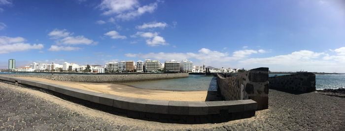 Buildings by sea against blue sky