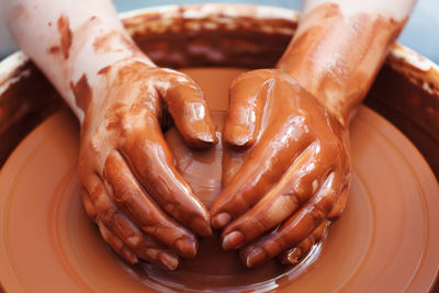 Cropped hands making clay pot