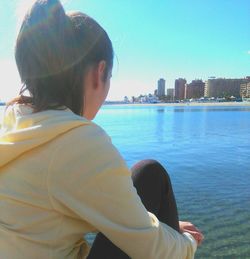 Rear view of woman against sea and cityscape