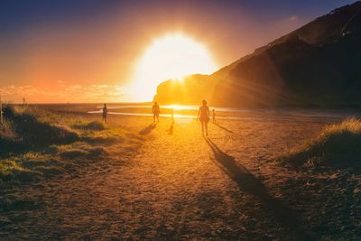 People on land against sky during sunset