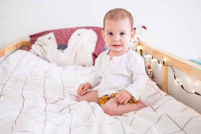 Portrait of cute girl sitting on bed at home