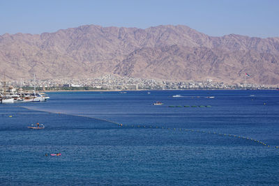 Scenic view of sea by town against clear blue sky