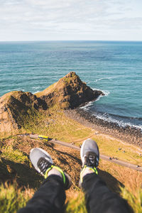 Low section of man sitting on hill against sea