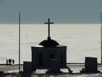 Cross on beach against clear sky