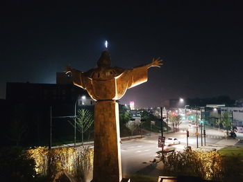 Statue in illuminated city against sky at night