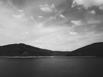 Scenic view of river by mountains against sky