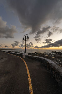 Empty road against sky at sunset