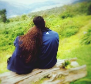 Rear view of woman sitting on grass