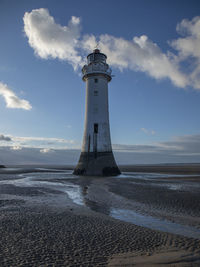 Lighthouse by sea against sky