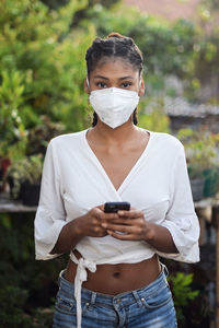 Young black woman in face mask using a smartphone