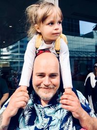 Portrait of smiling grandfather carrying granddaughter on shoulders