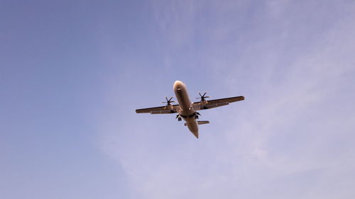 Low angle view of airplane flying against blue sky