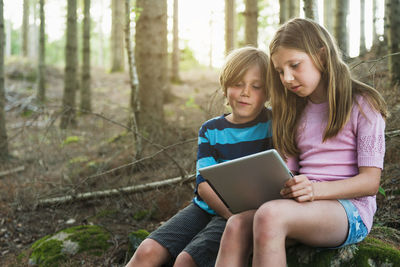 Boy and girl using digital tablet in forest