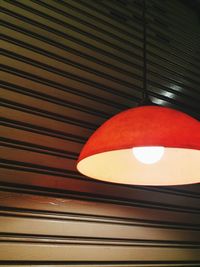 Low angle view of illuminated light bulb hanging from ceiling