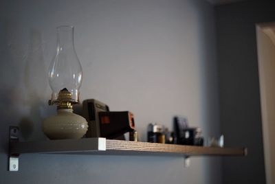 Old-fashioned lantern on shelf mounted on wall at home