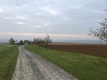 Road amidst field against sky
