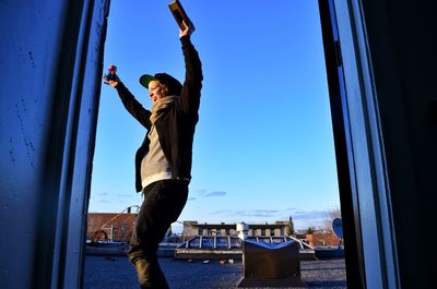 Full length of young man against blue sky